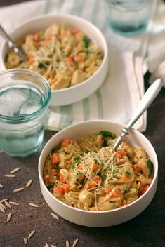 two bowls filled with pasta and vegetables on top of a table