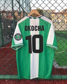 a green and white soccer jersey hanging on a fence