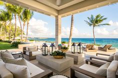 an outdoor living area with couches, chairs and lamps on the patio overlooking the ocean