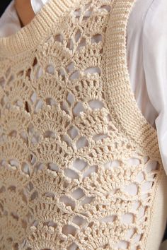 a crocheted sweater hanging on the back of a man's white shirt