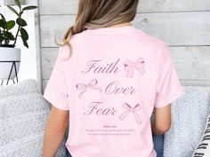 ABOUT THIS TEE 📖 Introducing our "Faith Over Fear" Christian Coquette Shirt, where faith meets fashion in a delightful blend of preppy pink bows and timeless scripture. This charming crewneck tee is adorned with sweet pink ribbons and not only uplifts the spirit but also serves as a thoughtful reminder of the power of faith over fear. Whether as a personal statement or a meaningful gift, embrace the strength found in faith with every wear. PRODUCT DETAILS 👕   - unisex jersey short sleeve tee - Inspirational Pink Crew Neck Top, Inspirational Pink Tops With Text Print, Cute Summer T-shirt With Pink Bow, Casual Short Sleeve T-shirt With Pink Bow, Pink Short Sleeve T-shirt With Bow, Casual Cotton T-shirt With Pink Bow, Cute Cotton T-shirt With Pink Bow, Faith Based Gifts, Butterfly Shirts