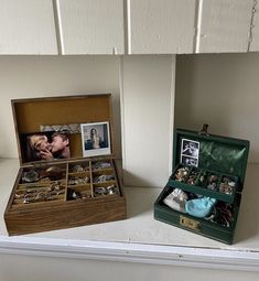 an open wooden box with pictures and jewelry in it sitting on a shelf next to other items