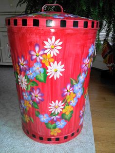 a red trash can with flowers painted on it