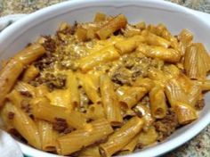 a white bowl filled with macaroni and cheese on top of a granite counter