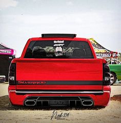 the back end of a red truck parked in front of other trucks at a car show