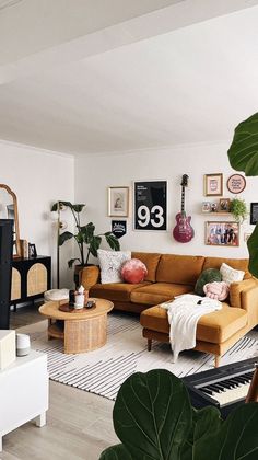 a living room filled with lots of furniture and plants on the wall above it is a piano