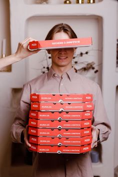 a man holding up a stack of pizza boxes