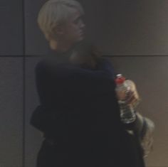 a woman with blonde hair is holding a bottle