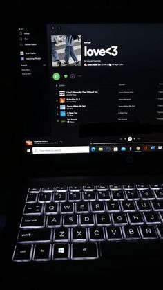 an open laptop computer sitting on top of a black table with the keyboard lit up