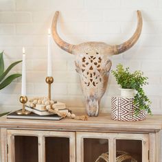 an animal head on top of a wooden cabinet next to candles and other decor items