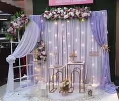 a white table topped with lots of flowers next to a purple and white curtained wall