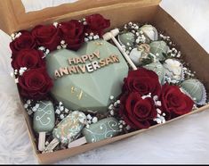 a box filled with lots of chocolates covered in frosted icing and roses