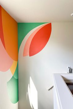 a bathroom with a large colorful wall mural in the corner and a sink below it