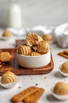 a bowl filled with peanut butter cookies on top of a wooden cutting board next to other desserts