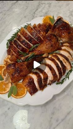 a white plate topped with sliced up chicken and oranges on top of a marble counter