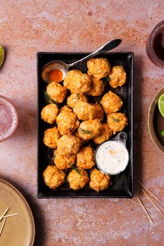 there is a tray with tater tots on the table next to other plates