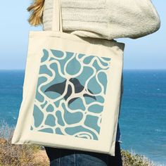 a woman carrying a tote bag with an image of a bird on the ocean