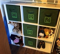 several green bins with stuffed animals in them on top of a white bookcase