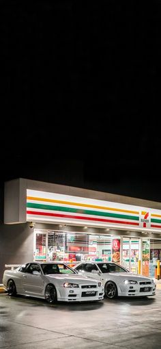 three cars are parked in front of a gas station at night with the lights on