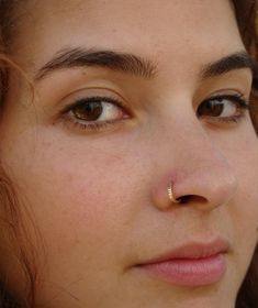 a close up of a person with a nose ring on her nose and an ear piercing