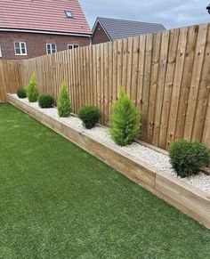 a fenced in backyard with grass and shrubs