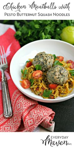 two meatballs with pesto butternut squash noodles in a white bowl next to a fork and napkin