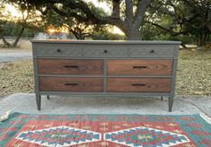 a dresser sitting on top of a rug next to a tree