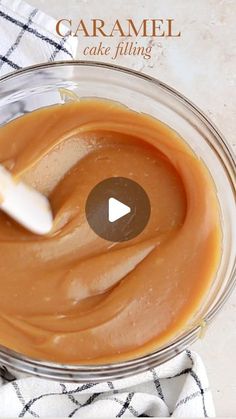 a glass bowl filled with caramel icing on top of a white and black towel