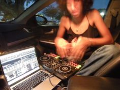 a woman sitting in front of a laptop computer next to a dj's mixer