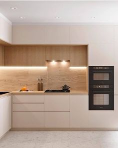 an empty kitchen with two ovens and a sink in the middle is illuminated by recessed lighting