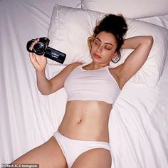 a woman laying in bed while holding a camera