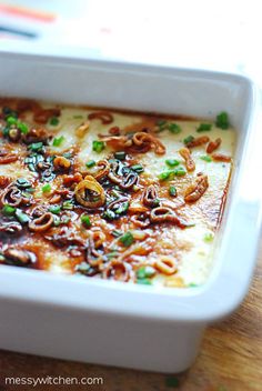 a casserole dish with meat and onions in it on a wooden table top