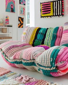 a multicolored crocheted couch and rugs in a room with pictures on the wall