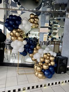 there are many balloons on display in the store window and one is blue, gold and white