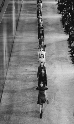 a row of people walking down a long hallway