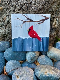 a painting of a red cardinal sitting on top of blue rocks next to a tree