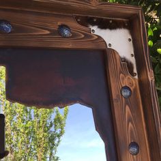 a mirror that is made out of wood and has metal studs on the frame