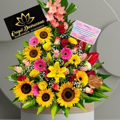 a bouquet of sunflowers and other flowers in a white vase with a card