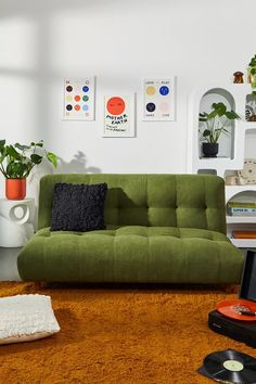 a green couch sitting on top of a brown rug in a living room next to a record player