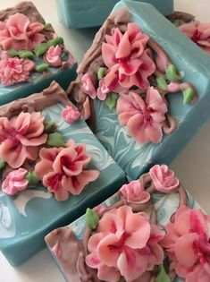 four soap bars decorated with pink flowers on a white tablecloth and blue trays