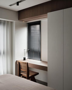 a bedroom with a bed, desk and chair next to a window that has blinds on it