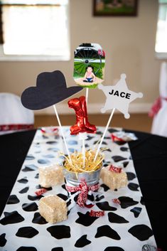 a black and white table topped with cupcakes and marshmallows covered in chocolate