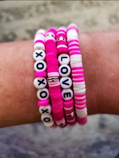 a person's arm with pink and white bracelets that say i love you