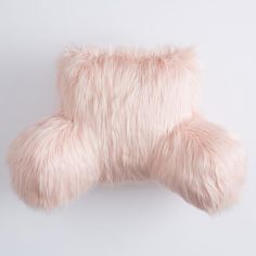 a pink furry pillow sitting on top of a white wall