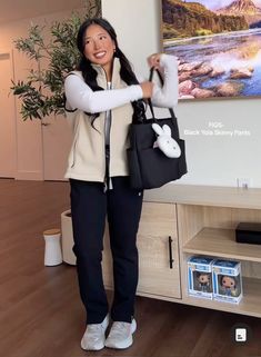 a woman holding a black purse in front of a television