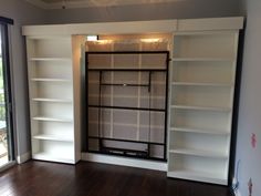 an empty room with white bookcases and sliding glass doors