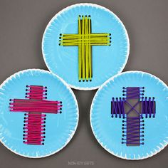 three paper plates decorated with colored sticks and a cross