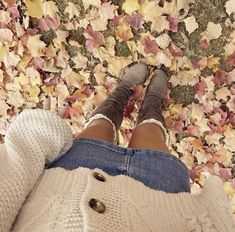 a person standing in front of leaves with their feet on the ground and legs crossed