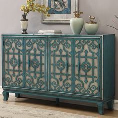 an ornate blue cabinet with two vases on top of it next to a painting