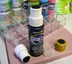 several different colors of acrylic paint on a pink tray with plastic cups and containers